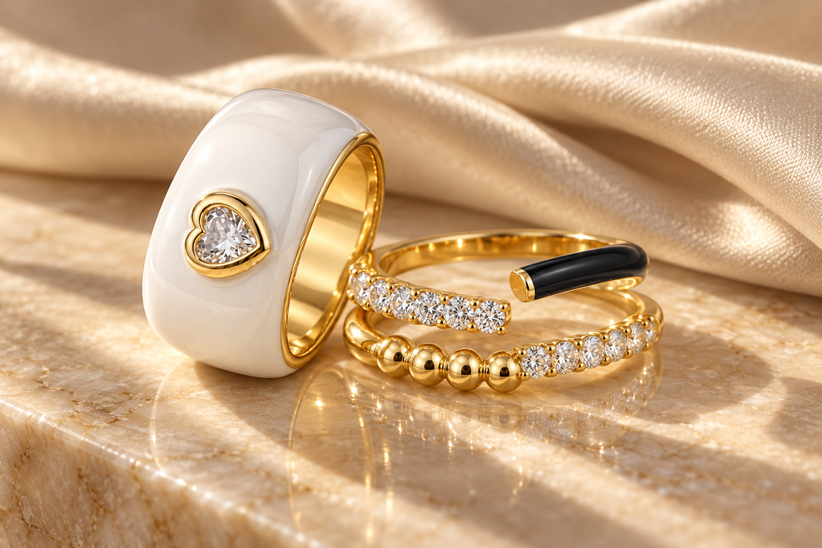 White enamel heart ring and black enamel and gold bead wrap rings on champagne satin and stone
