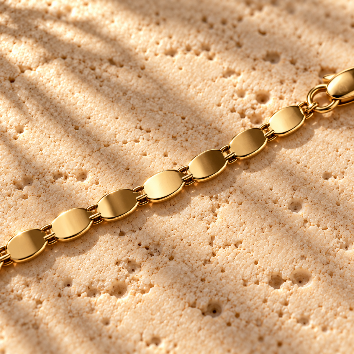 Bar None Gold Cobra Chain macro close-up: flat polished oval gold plates linked toward the lobster clasp