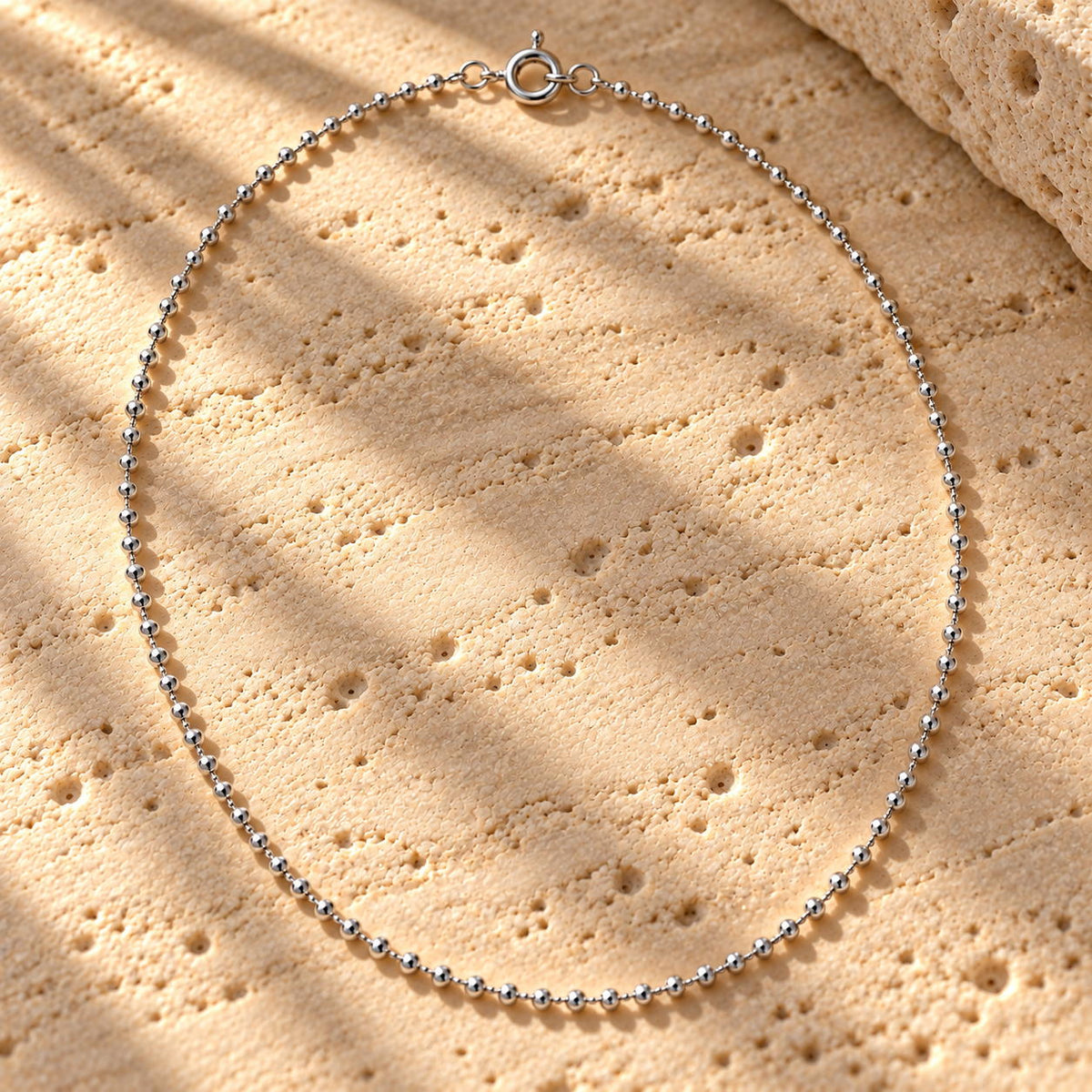 Bar None bead chain in sterling silver laid on travertine, polished beads and spring-ring clasp