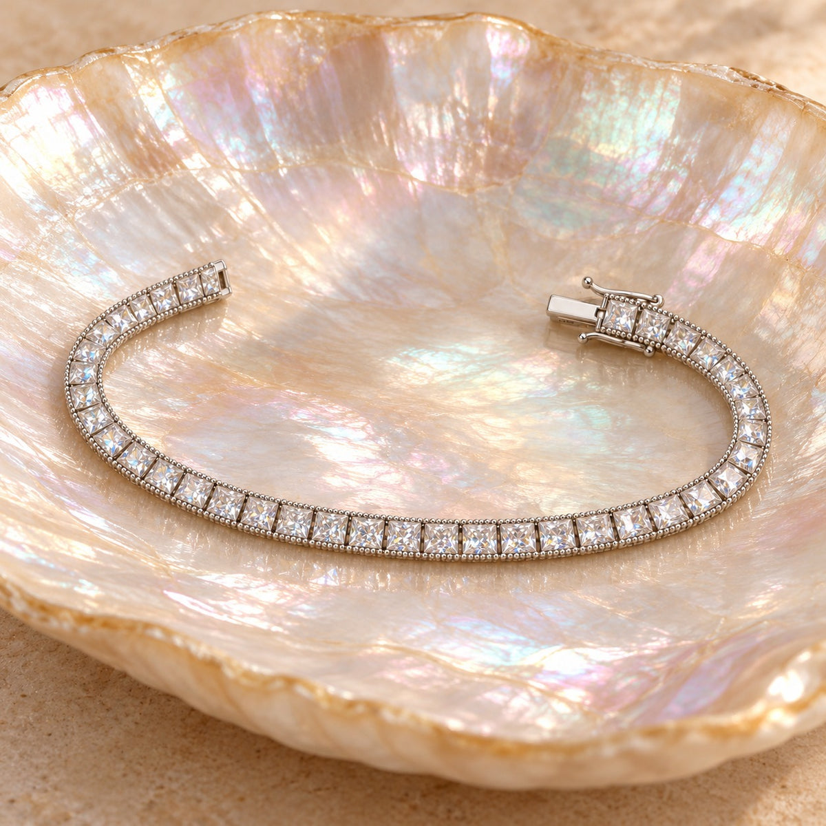Fair and Square tennis bracelet open on a shell dish, showing the box clasp and safety latch