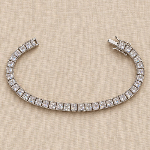 Fair and Square tennis bracelet full length on linen — square princess-cut stones with a beaded edge, box clasp
