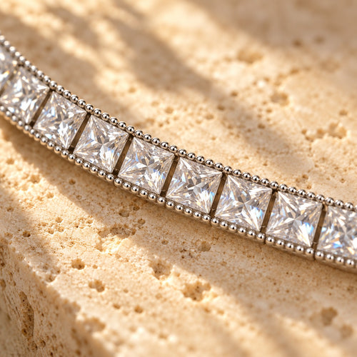 Fair and Square close-up — square princess-cut stones framed by a beaded silver edge on travertine