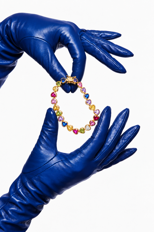 Heart Throb Tennis rainbow heart bracelet held in cobalt blue leather gloves